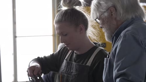 Woman Adjusting Wood Plane While Man Watches