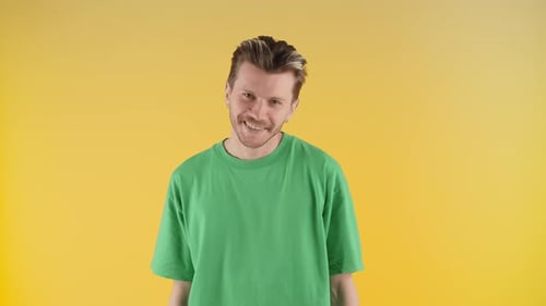 Homme souriant posant sur un fond jaune Un jeune homme en t-shirt vert danse devant