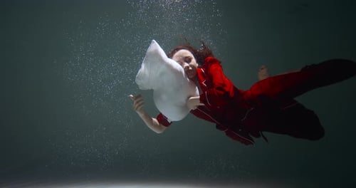 Tournage Cinématographique : une belle femme métisse en pyjama rouge s'enfonce sous l'eau pour s'endormir