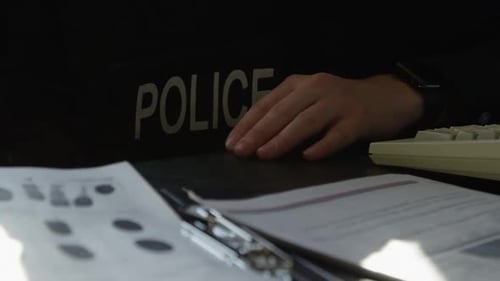 Police Officer Reviews Documents at Desk