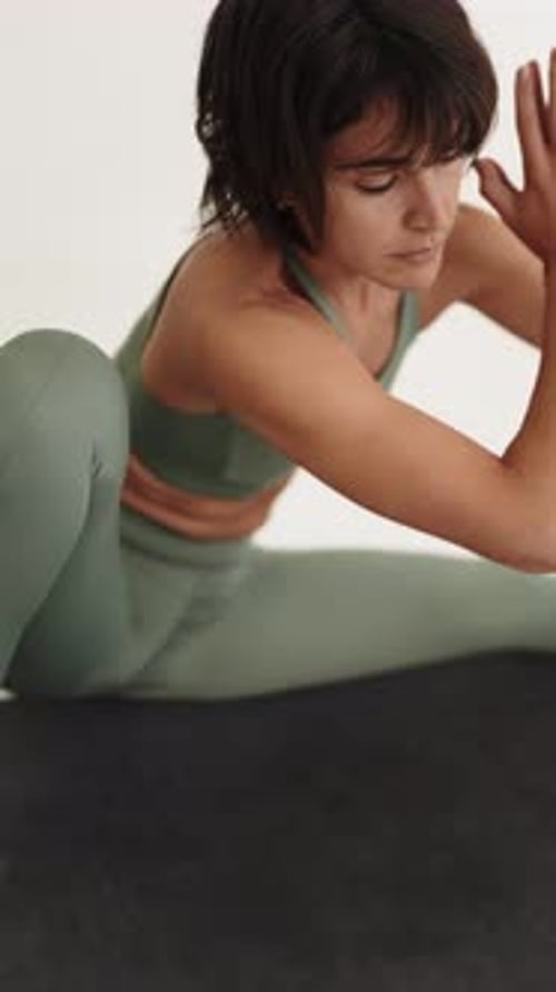 Jeune femme concentrée pratiquant le Skandasana dans un studio de yoga