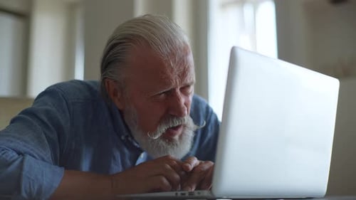 Senior Man Working on Laptop Inside Home