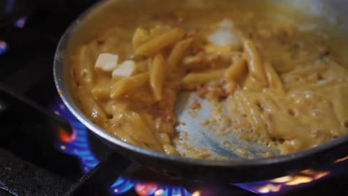 Cheese Melting On Pasta With Sauce While Chef Tossing And Stirring On Pan. - close up