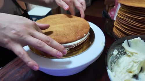 Hands Assembling Cream Layered Cake on Rotating Stand