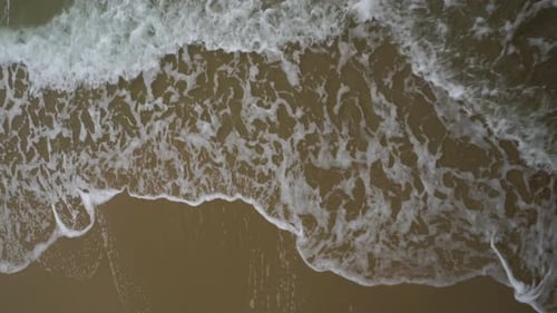 Close Up of Waves White Water Rolling Gently up the Sandy Beach.