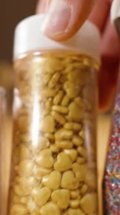 Vertical video. Close-up slider, a pastry chef choosing sugar sprinkles for decorating pastries.