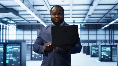 IT Engineer Working on Laptop in Data Center Overseeing Server Operations