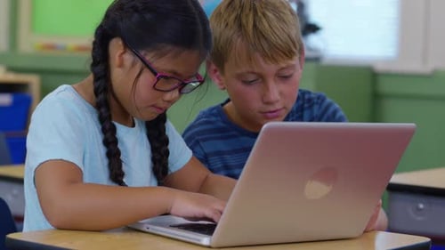 Two Students Work on Laptop Computer Together in School Classroom Child
