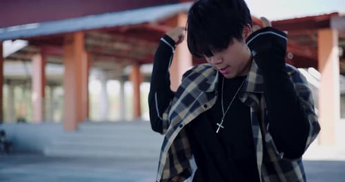 A hip-hop young man enjoys freestyle dancing in an outdoor pavilion.