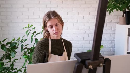 Beautiful female artist painting picture in art studio.