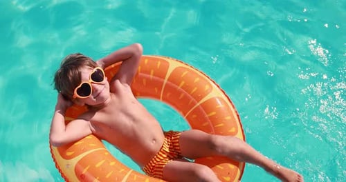 Boy Relaxing on Float in Aqua Swimming Pool