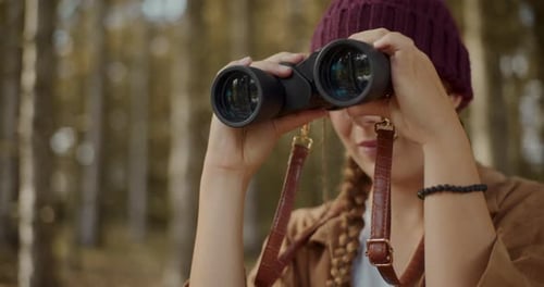 Woman Looking Through Binoculars in Forest