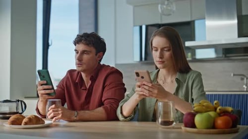 Young Couple Using Smartphones in Modern Kitchen
