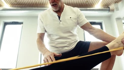 Senior Man Assists Person with Resistance Band Exercise