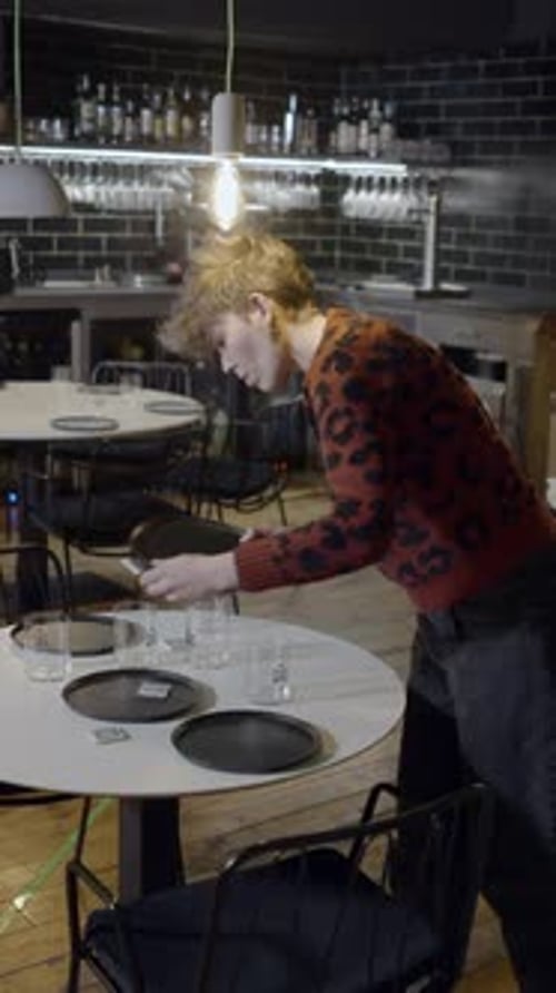 Slomo de una joven moviendo platos de la mesa redonda de un restaurante