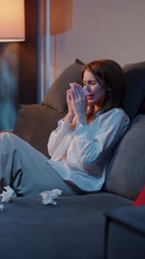 Woman Sitting on Couch Crying and Wiping Tears