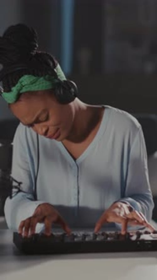 Woman plays keyboard at table in dimly lit room
