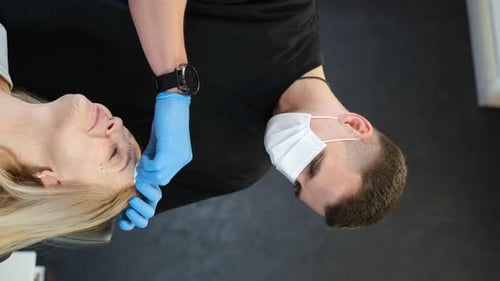 Vertikales Videoporträt eines Arztes und einer älteren Frau bei der Vorbereitung auf die plastische Chirurgie
