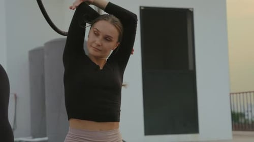 Young Woman Stretching on an Urban Rooftop at Sunrise