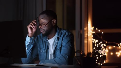 Man Financial Analyst Studying Report on Laptop Late in Evening Taking Off Eyeglasses and Rubbing