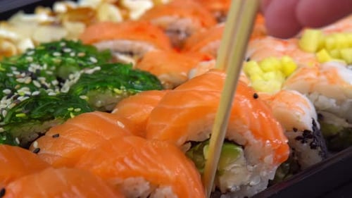 Cocina japonesa con mariscos. Poner un rollo de sushi del set con palitos para sushi. Sostenga la mano
