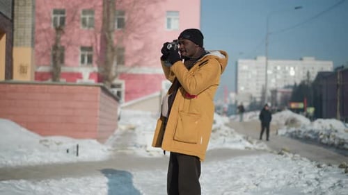 Professional Photographer Capturing Winter Street Shots on Snowy Sunny Sidewalk