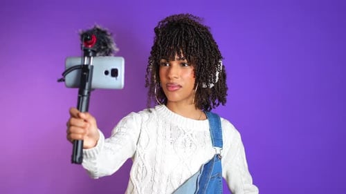 Young latin influencer recording content with smartphone and microphone