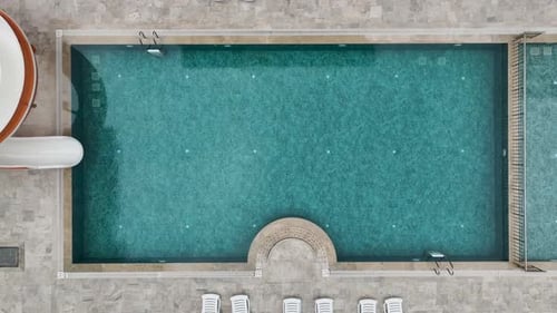 Aerial Video of Resort Pool with Spiral Slide and Loungers Placed on Tiled Terrace