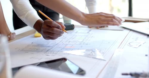 Reviewing architectural blueprints, business professionals collaborating on project plans in office