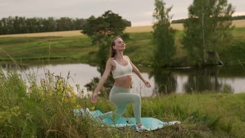 Woman Does Yoga by Pond in Field