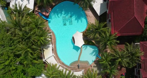A cinematic dolly-out drone shot reveals a luxurious resort pool, expanding to showcase its serene s
