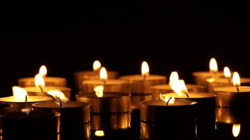 Close Up of Flickering Candles Against Black Background
