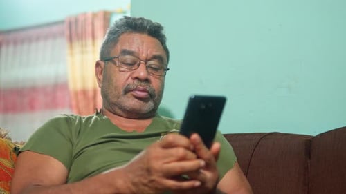 Man Sitting on Couch Using Cellphone Indoors
