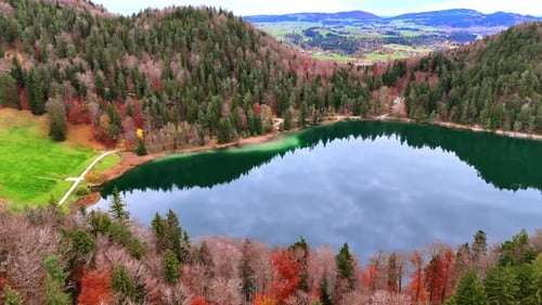 Scenic view of a lake surrounded by forests and mountains during autumn.
