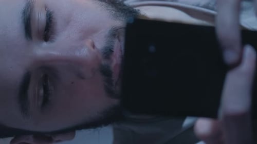 Young Man Uses Smartphone in Bed at Night