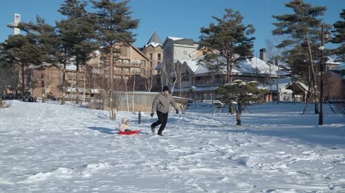 Little Girl Falls Out Of Sled on Snow While Being Pulled By Father Sledding Downhill at Alpensia Vil