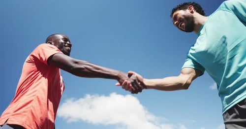 Athletic Men Give Fist Bump Against Clear Blue Sky