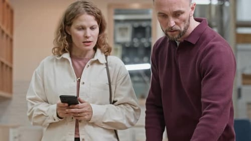 Woman Texting on Social Network while Man Measuring Table with Tape Measure