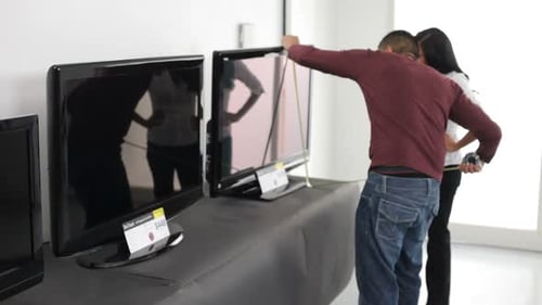 Couple Comparing and Measuring Televisions in Retail Store