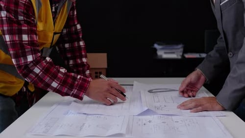 Close up of hands working for cost estimating on floor plan drawings.