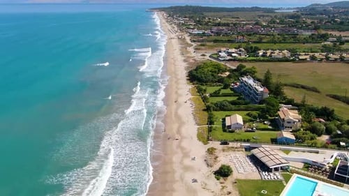 Aerial View of Long Sandy Beach with Turquoise Waves and Luxury Beachfront Resorts in Corfu Greece,
