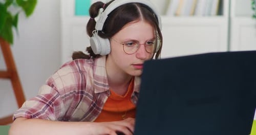 Teenager Uses Laptop with Headphones in Home