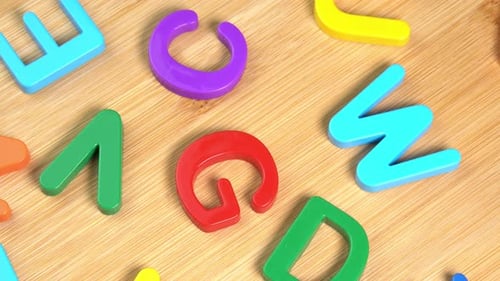 Multicolored letters rotate on a wooden background. The concept of learning, school or college
