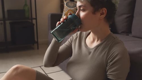 Young Woman Drinks Refreshment at Home with Prosthetic Arm