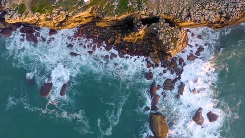Aerial top view of waves break on rocks. Aerial drone top down view bird eye view of sea blue waves