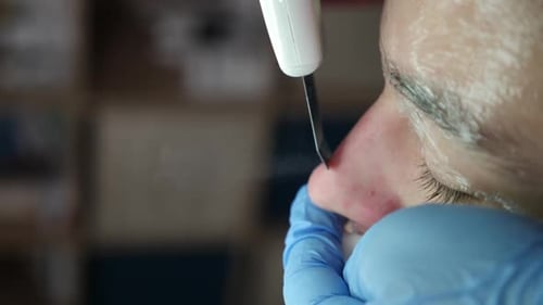 Kosmetikerin verwendet Ultraschall-Hautwäscher, um Schmutz und abgestorbene Hautzellen im Gesicht in Zeitlupe zu entfernen