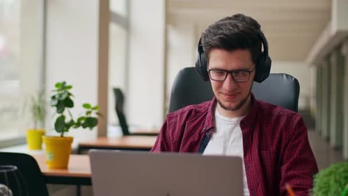 Young Adult Working on Laptop Wearing Headphones