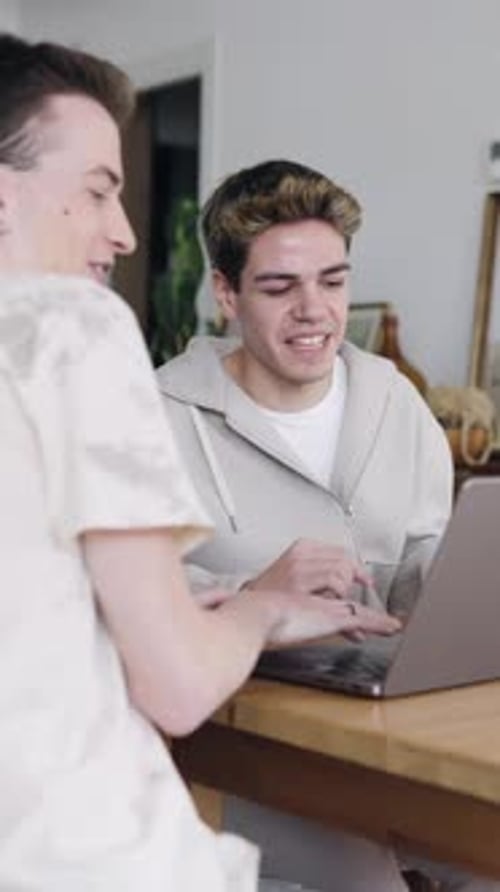 Young Gay Couple Collaborating on Laptop Project at Home Vertical