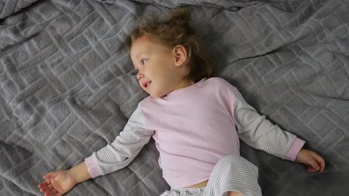 Happy Child Lying on Bed Laughing