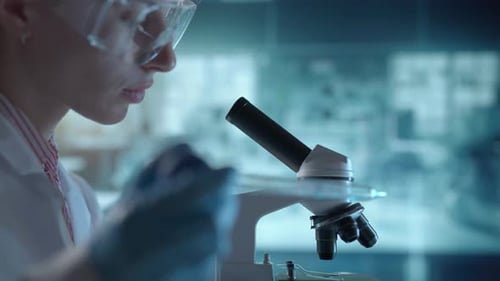 Laboratório de Ciências Médicas Um microbiologista usando óculos está examinando o microscópio